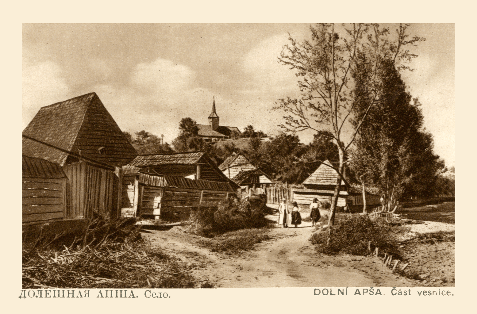 Sepia postcard from the 1920s: a dirt road through the village of Dolishnia Apsha, three women walking toward a church on the hill