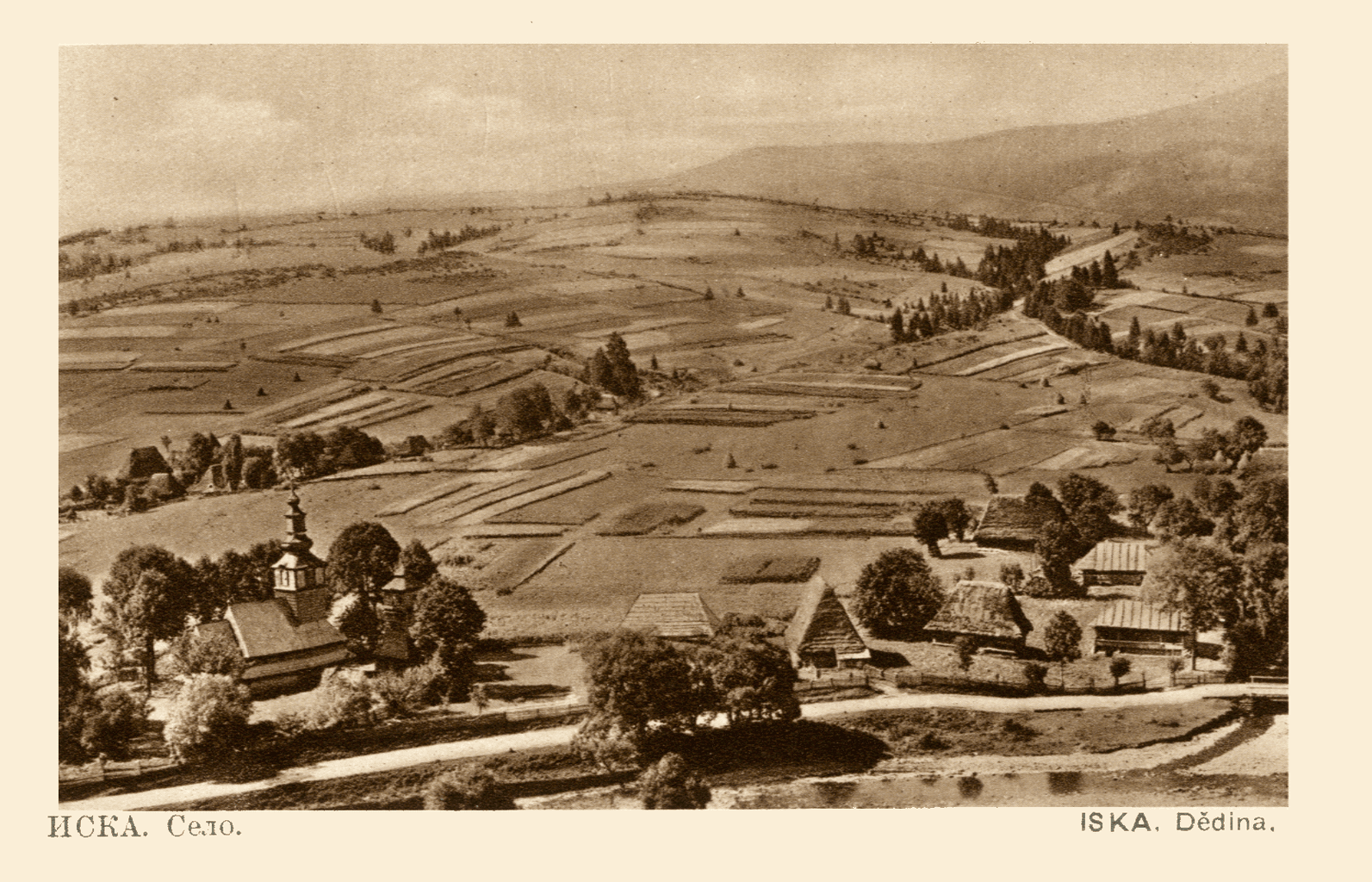 Sepia postcard from the 1920s: the village of Iska in Zakarpattia — a wooden church among houses, fields on the hills behind